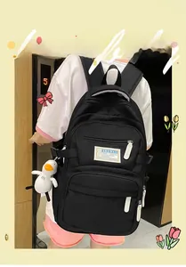 Detailed view of a black multi-pocket nylon backpack with white zippers and duck charm