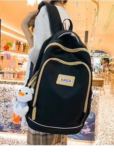 Close-up of black backpack with cream trim, including a cute duck plush keychain detail
