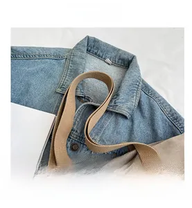 Close-up of beige canvas tote bag showing wide woven strap and durable fabric texture