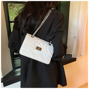 Vue arrière d'un mannequin portant un sac matelassé blanc sur une veste de blazer noire