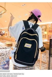Detailed view of large black casual backpack with a cute white duck charm in a cafe