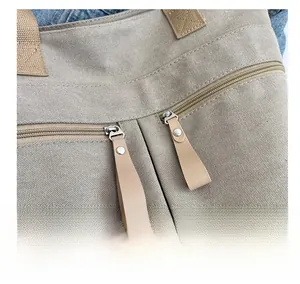 Close-up of canvas tote bag with dual zippers and leather pullers for durable use