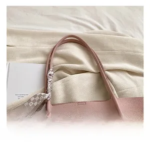 Close-up of pink litchi grain leather tote bag handle with checkered decorative scarf