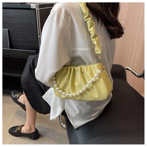 Detail of lime green ruched cloud bag with large pearl strap and gold hardware