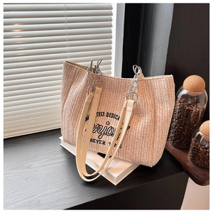 Detail of woven straw tote bag with Enjoy typography and chain faux-leather strap