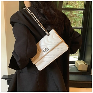 Détail du sac bandoulière en cuir blanc matelassé avec chaîne argentée sur l'épaule