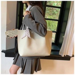 Macro shot of cream-colored pebble leather tote bag with gold fashion lettering logo