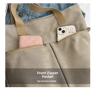 Detail view of the front double zipper pockets on this khaki canvas tote bag