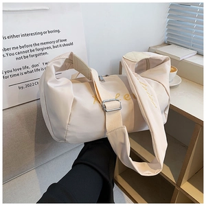 Detail of cream Oxford fabric bag with yellow embroidery and wide adjustable strap