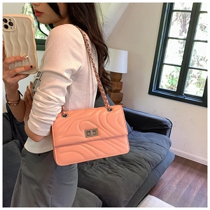 Détail du sac bandoulière orange clair avec matelassage ondulé et fermoir rotatif en métal