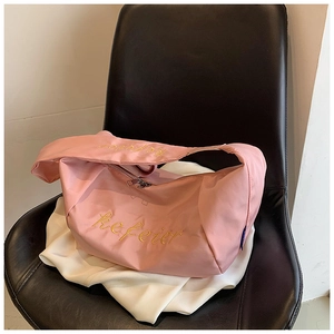 Detailed view of pink nylon crescent bag with yellow script embroidery on black leather