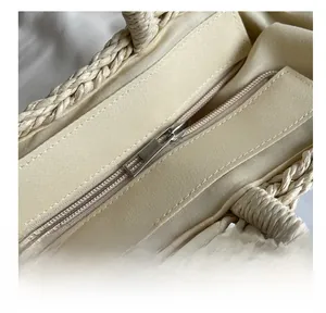 Detail shot of the smooth metal zipper and woven texture of the straw beach bag