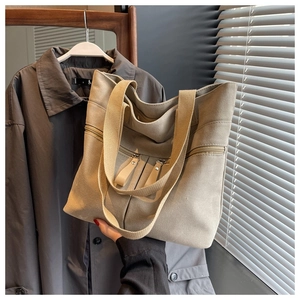 Detail of khaki canvas tote bag featuring double front zipper pockets and texture