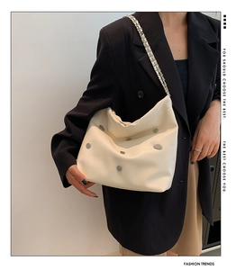 Detail of cream large hobo bag with metal studs and silver chain shoulder strap