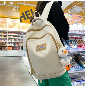 Close-up of beige casual backpack with duck pendant in a supermarket setting