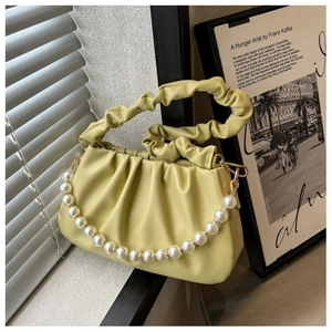 Close-up of pale yellow pleated cloud bag featuring large white pearl chain detail
