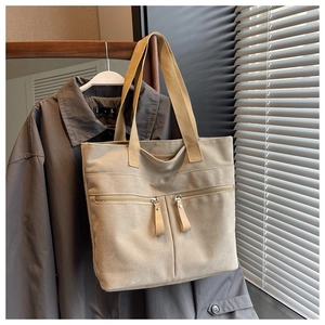 Detail view of canvas tote bag with dual zipper pockets and long shoulder straps
