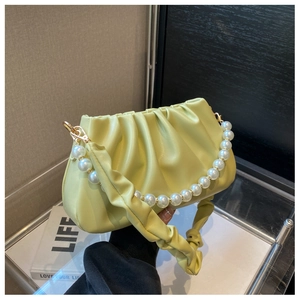 Detail of light yellow cloud bag with pleated texture, pearl handle and gold hardware