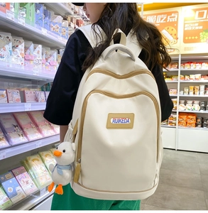 Detail of beige nylon backpack with contrast brown zippers and cute duck plush charm