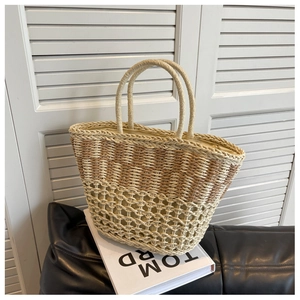 Detail of two-tone woven straw tote bag with mesh hollow design and cylindrical handles