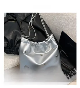 Detail of silver metallic tote bag with studs, chain strap and drawstring design