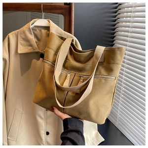 Detailed view of the dark khaki canvas tote bag featuring dual front zipper pockets