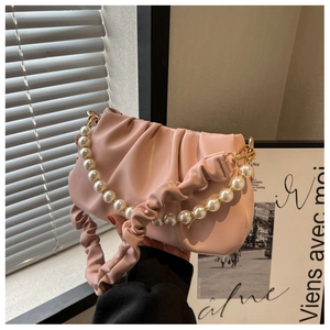 Close-up of pink pleated cloud bag featuring pearl chain and ruched strap detail