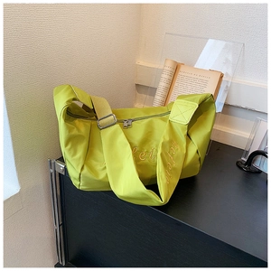 Detail of lime green nylon dumpling bag with wide strap and embroidery on side angle