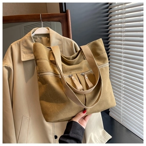 Detailed view of the khaki canvas tote bag featuring dual front zipper pockets
