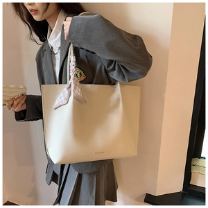 Detail of off-white large tote bag with gold fashion text and decorative silk scarf