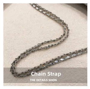 Detail of silver metal chain interwoven with light gray leather strap on shoulder bag