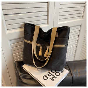 Detail of a charcoal canvas tote bag with beige straps and multi-pocket design