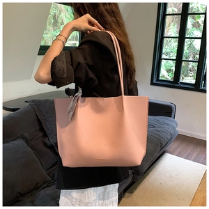 Detailed macro of pink lychee leather tote bag featuring fashion text and silk scarf