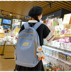 Detailed side view of light blue backpack with adjustable straps and plush duck charm