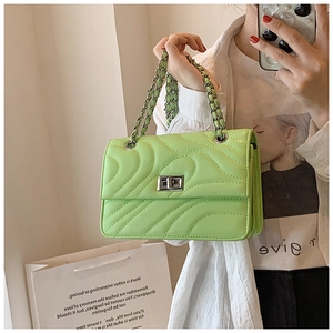 Détail d'un mini sac bandoulière vert néon matelassé avec fermoir rotatif argenté