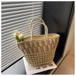 Detailed close-up of woven straw beach bag with striped patterns and dual handles