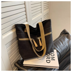 Detail of black canvas tote bag with khaki straps and front zipper pocket design
