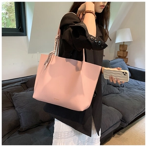 Detail of pink pebbled leather tote bag featuring a decorative scarf and thin shoulder strap
