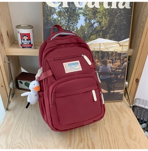 Detail of burgundy large capacity backpack with multiple pockets and cute duck charm