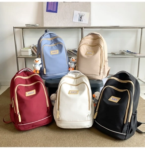 Five assorted colors of nylon backpacks with cute duck pendants on a display shelf