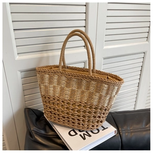 Detail of two-tone woven straw beach bag with hollow mesh design and fabric lining