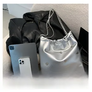 Size comparison of silver chain bucket bag with rivets next to an iPad and iPhone
