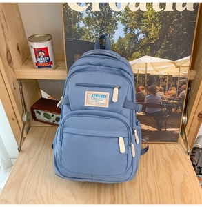 Detail of light blue casual backpack with brand label on a wooden shelf setting