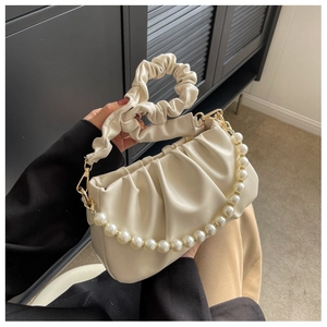 Close-up of cream white cloud bag with pearl chain and soft pleated leather texture
