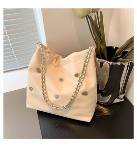 Close-up of cream PU leather bucket bag with silver heart studs and chain strap