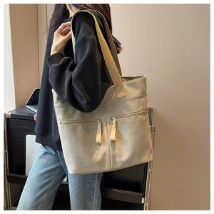 Detail of high-capacity canvas tote bag featuring dual front zipper pockets and wide straps