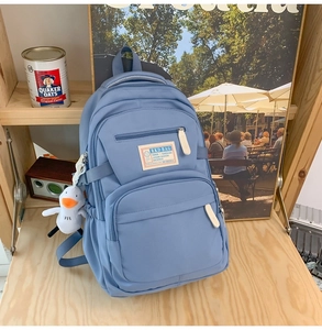 Detail of light blue nylon backpack with RKD brand label and white plush duck charm