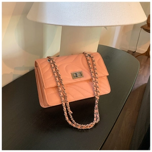 Sac bandoulière matelassé rose avec texture ondulée et fermoir argenté sur surface noire