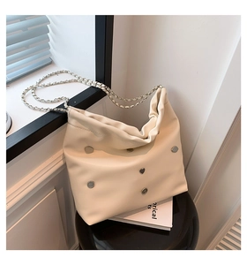 Detail of off-white leather bucket bag featuring silver chain strap and heart stud