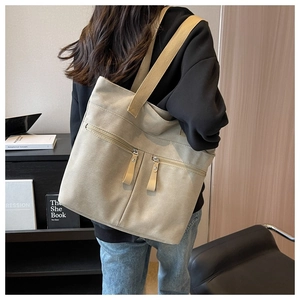 Detailed view of beige canvas tote bag with functional zippers and wide shoulder strap